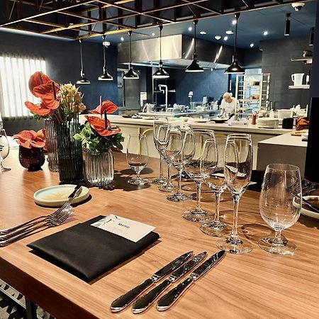 Aparthotel Royal Tulip Warsaw Centre Exterior foto The photo shows a beautifully arranged dining area in a restaurant. There is a long wooden table set with elegant glassware, including wine glasses and water glasses. Each place setting includes polished silverware and a folded napkin with a card on 