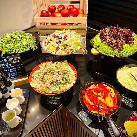Aparthotel Royal Tulip Warsaw Centre Exterior foto The photo shows a well-arranged salad bar featuring a variety of fresh salads and ingredients. There are several bowls and dishes with different types of salads, including green salads and grain salads. 

1. **Green Salads**: There are multiple bowls