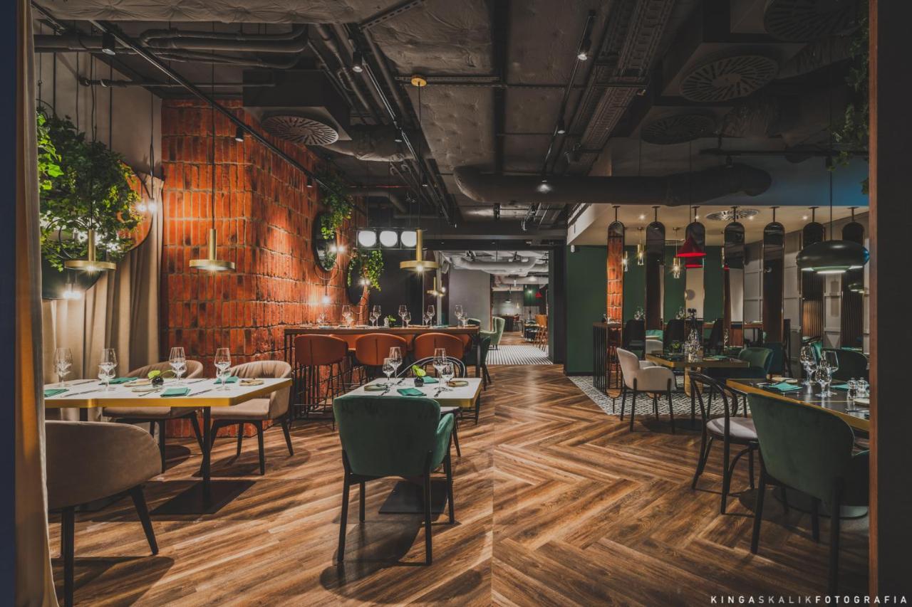 Aparthotel Royal Tulip Warsaw Centre Exterior foto The photo shows the interior of a modern restaurant. The design features a mix of wood and industrial elements, with a warm and inviting atmosphere. There are wooden floors laid in a herringbone pattern, and the walls have a combination of brick and 