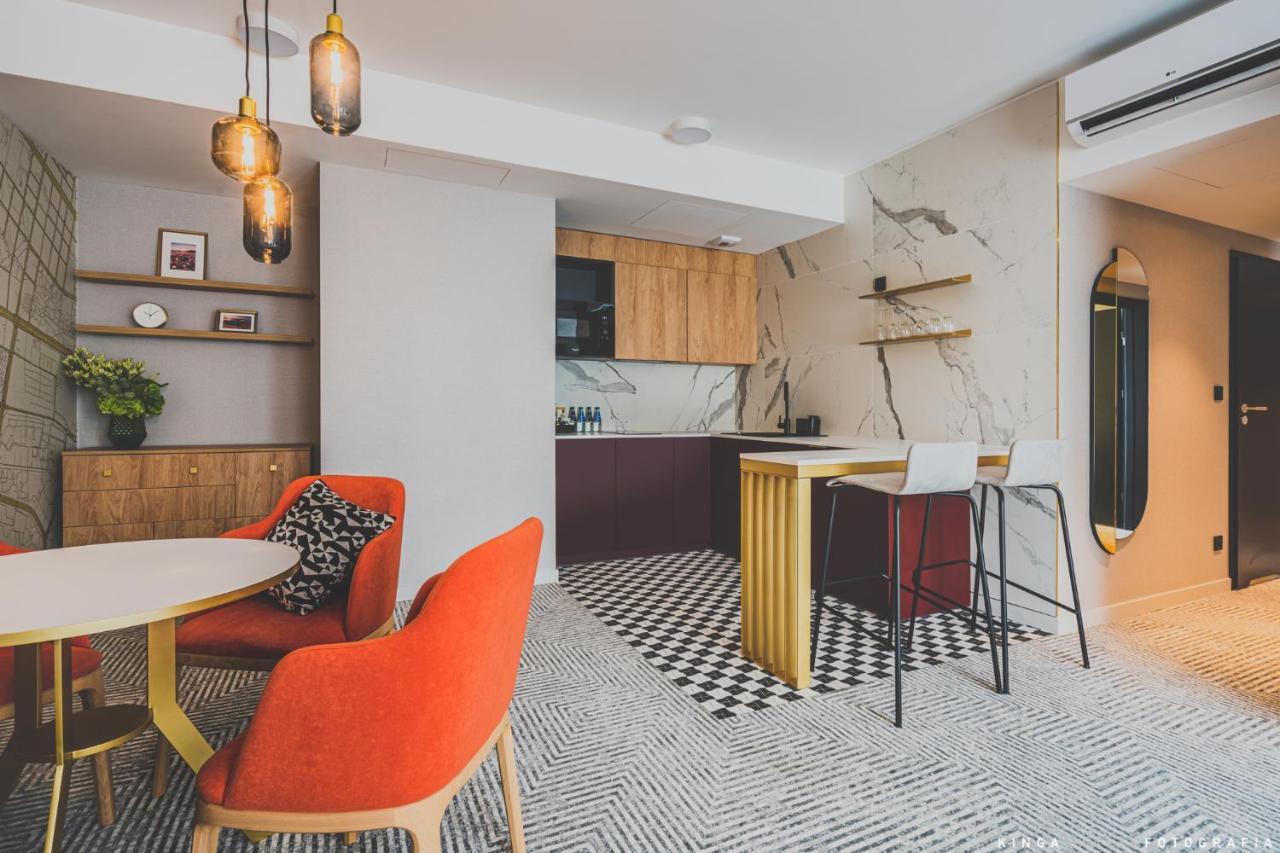 Aparthotel Royal Tulip Warsaw Centre Exterior foto The photo shows a modern interior space, likely a kitchen and dining area. 

- **Kitchen Area**: The kitchen features a combination of wooden cabinets and a dark-colored countertop. There's a marble backsplash that adds a sleek touch. It has an open 
