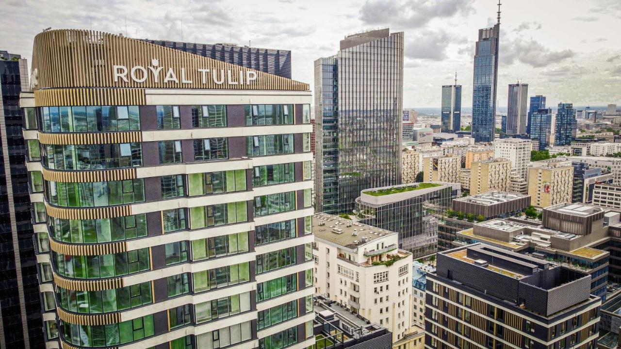 Aparthotel Royal Tulip Warsaw Centre Exterior foto The photo shows a cityscape featuring several modern skyscrapers and buildings. Prominently displayed in the foreground is the "Royal Tulip" hotel, characterized by its contemporary architectural design with large windows. Surrounding it are other ta