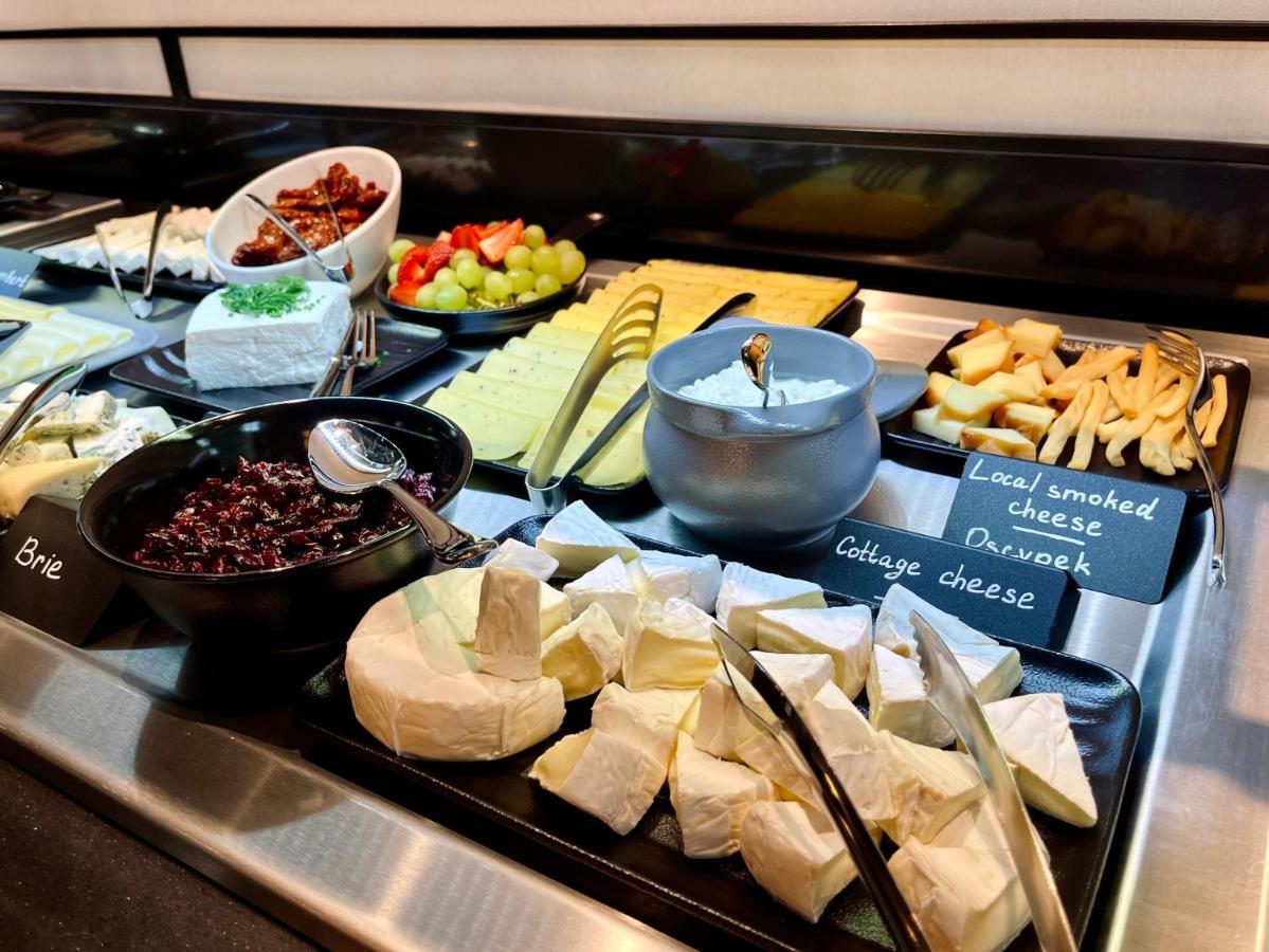 Aparthotel Royal Tulip Warsaw Centre Exterior foto The photo shows a variety of cheeses and accompaniments arranged on a buffet display. There are several types of cheese, including Brie and a soft cheese that appears to be cottage cheese. There's also a bowl of dark-colored cheese, likely a spread. 