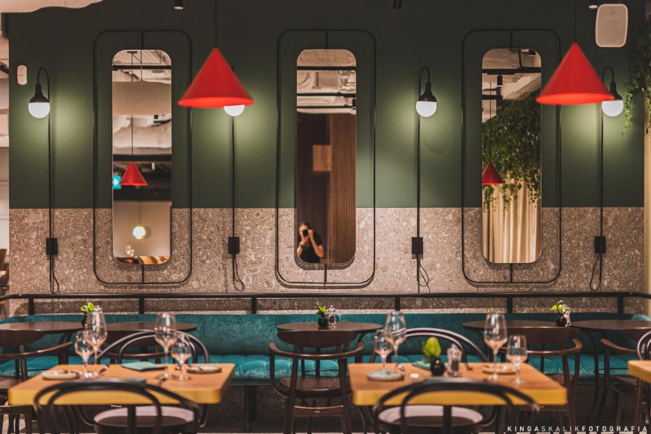 Aparthotel Royal Tulip Warsaw Centre Exterior foto The photo depicts a modern restaurant interior characterized by a stylish design. The walls are painted in dark green, featuring several mirrors set in unique frames. Bright red pendant lights hang from the ceiling, adding a pop of color to the space