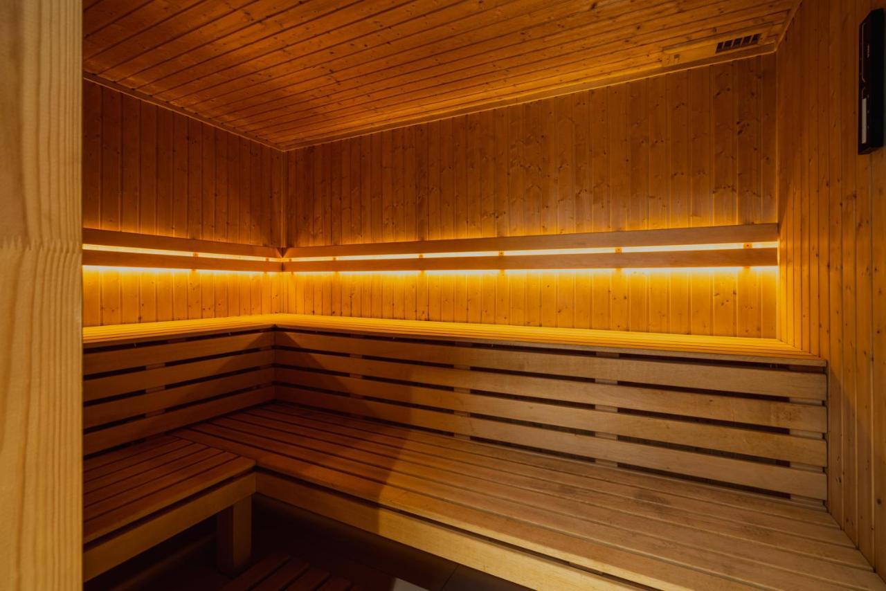 Aparthotel Royal Tulip Warsaw Centre Exterior foto The photo shows the interior of a sauna. It features wooden walls and benches, creating a warm and cozy environment. The lighting is dim but highlights the wood's natural grain, contributing to a relaxing atmosphere. The design includes benches that 