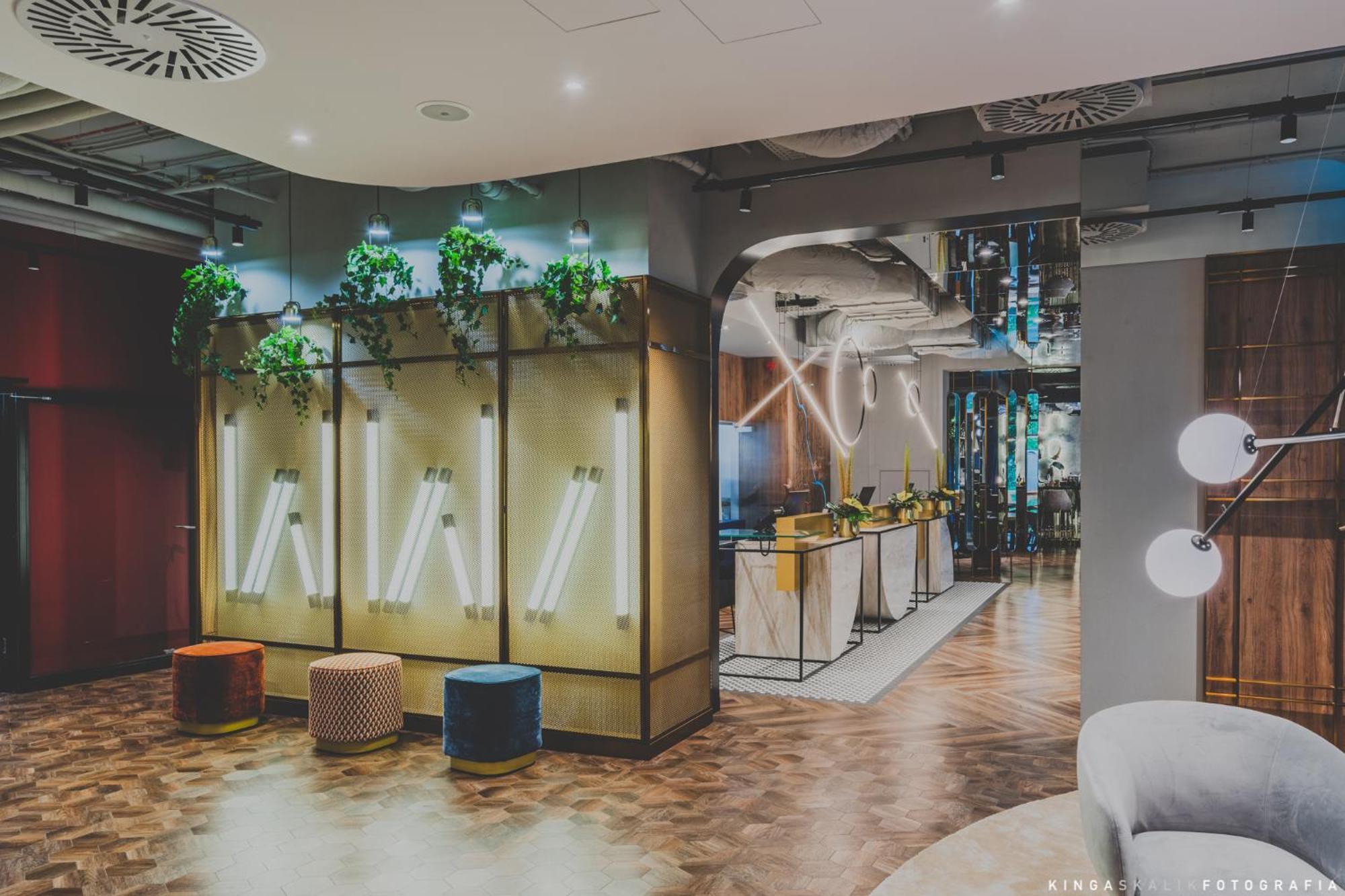 Aparthotel Royal Tulip Warsaw Centre Exterior foto The photo shows a modern interior space, likely a lobby or lounge area. The design features a combination of stylish furniture and decorative elements. There are illuminated wall panels integrated with greenery, creating a fresh aesthetic. In the bac