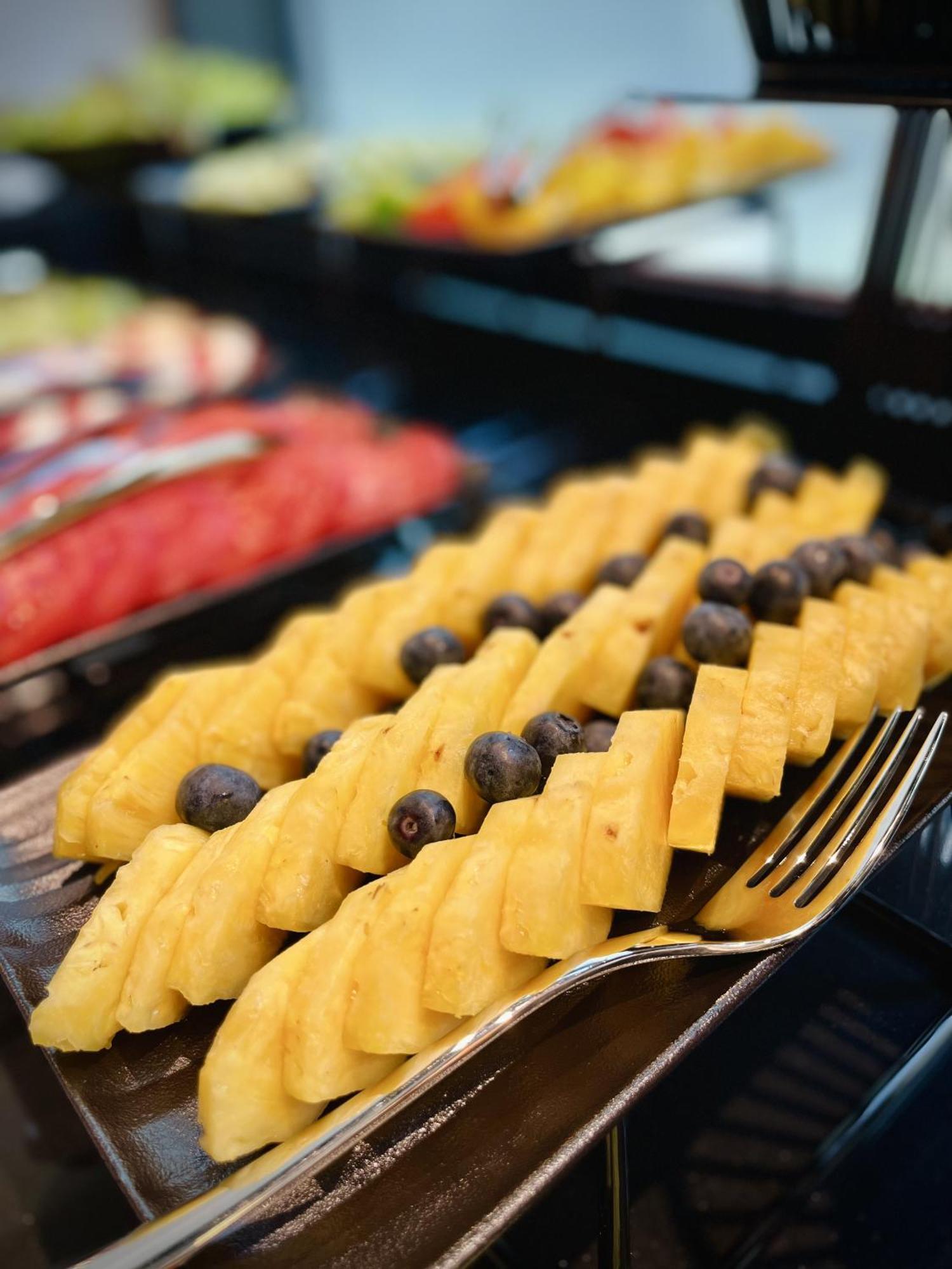 Aparthotel Royal Tulip Warsaw Centre Exterior foto The photo shows a colorful fruit display featuring neatly arranged slices of yellow pineapple, interspersed with dark blueberries. The pineapple slices are cut into a checkerboard pattern, creating an appealing presentation. In the background, other 