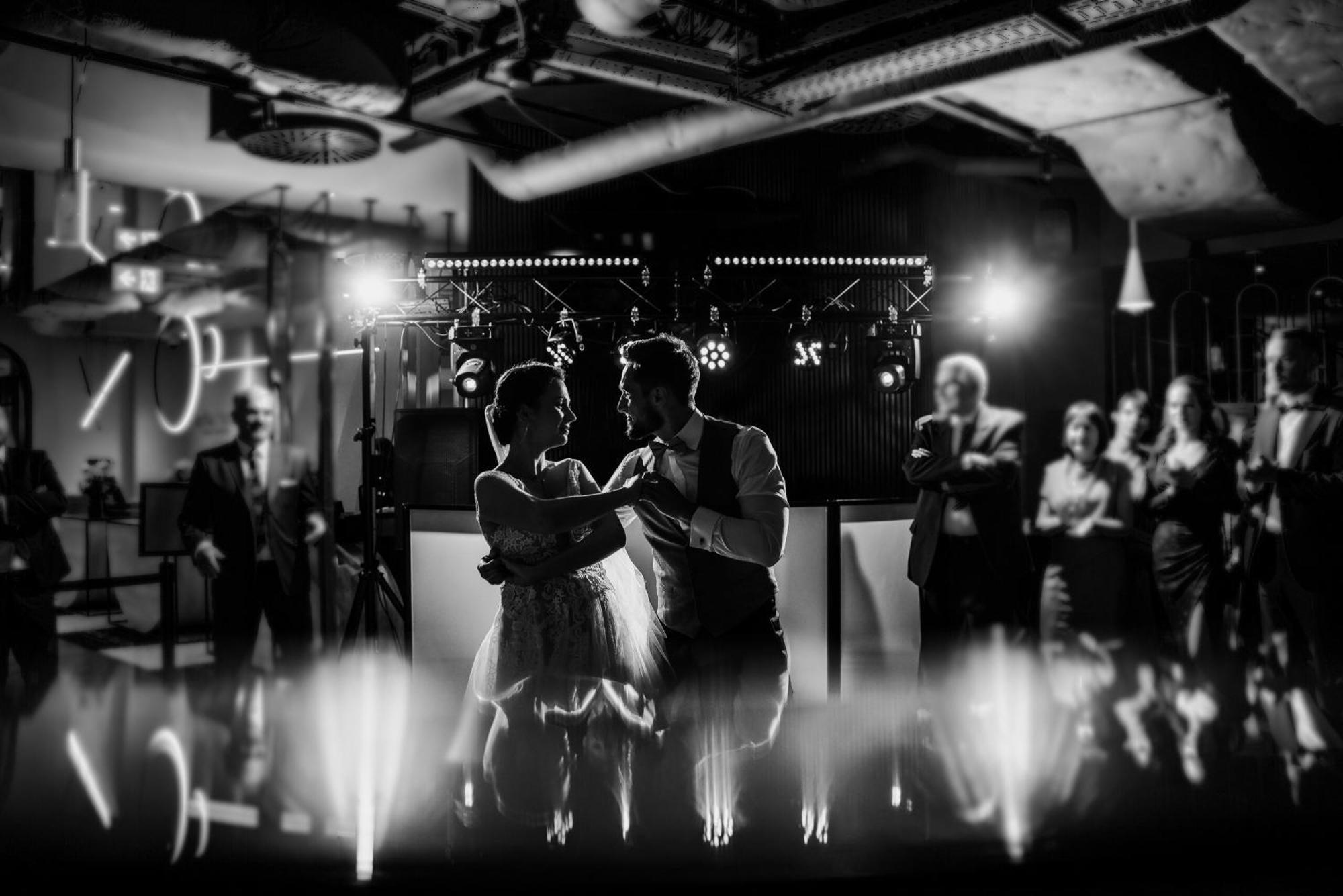 Aparthotel Royal Tulip Warsaw Centre Exterior foto The photo depicts a couple dancing together in an elegant setting, likely during a celebration such as a wedding. The scene is captured in black and white, emphasizing the intimate atmosphere. In the background, there are people observing and enjoyin