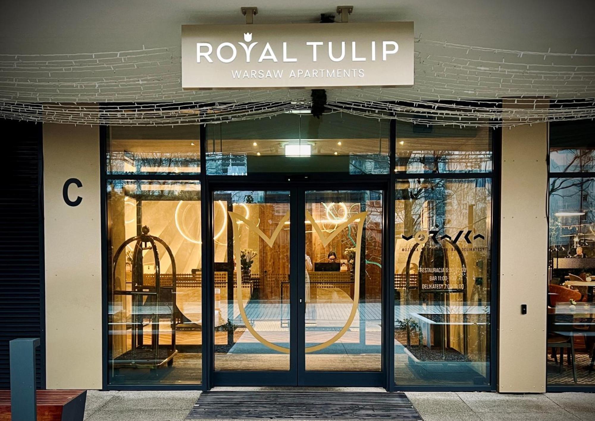 Aparthotel Royal Tulip Warsaw Centre Exterior foto The photo shows the entrance to a hotel named "Royal Tulip." The facade features large glass doors that allow a view into the lobby area. There are decorative elements, including what appears to be luggage carts near the entrance. Above the doors is 