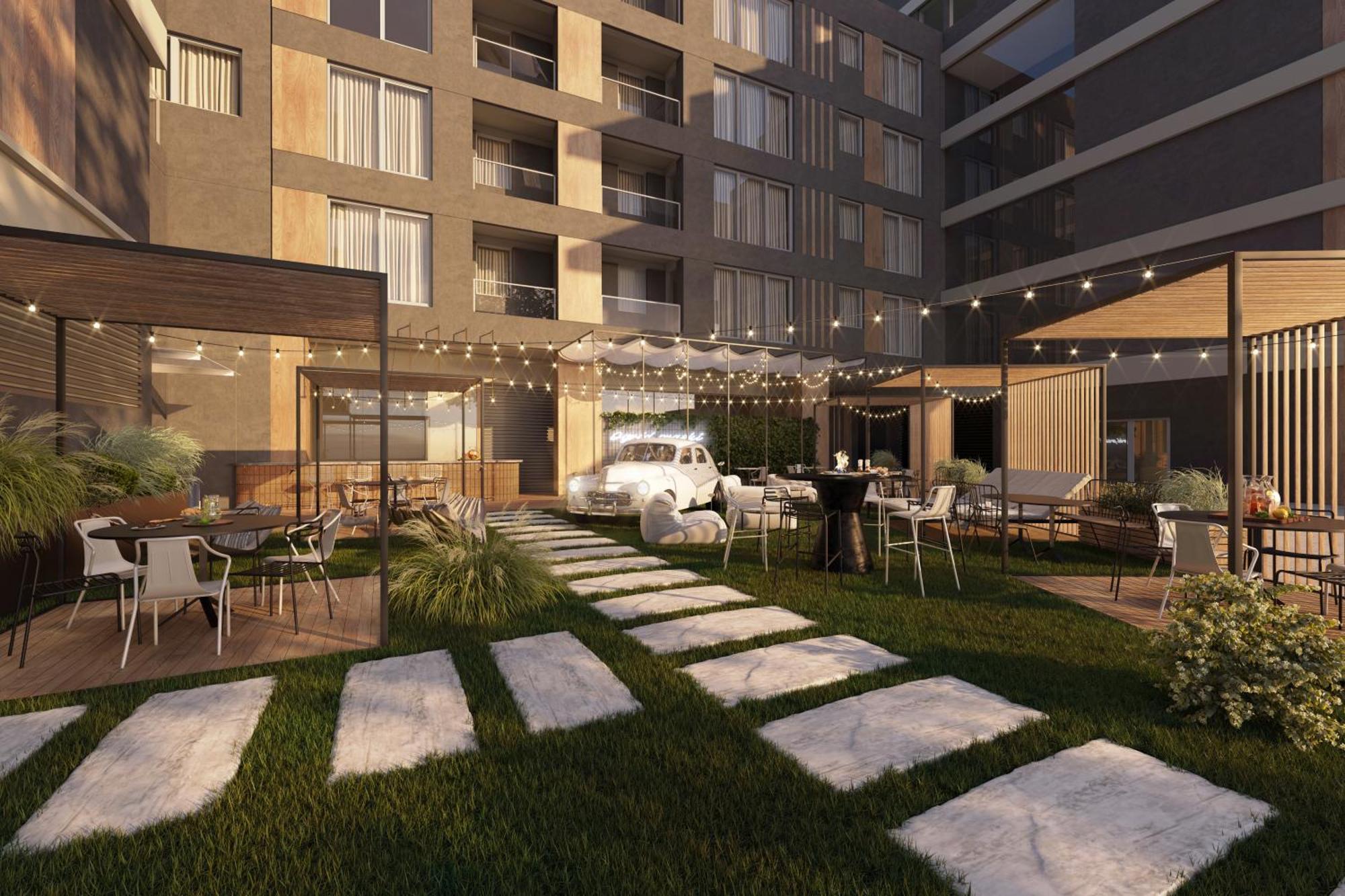 Aparthotel Royal Tulip Warsaw Centre Exterior foto The photo shows a modern outdoor space in an apartment complex or residential building. It features a neatly landscaped area with a lawn, stone pathways, and neatly arranged outdoor seating. There are multiple tables and chairs, some under cozy canop
