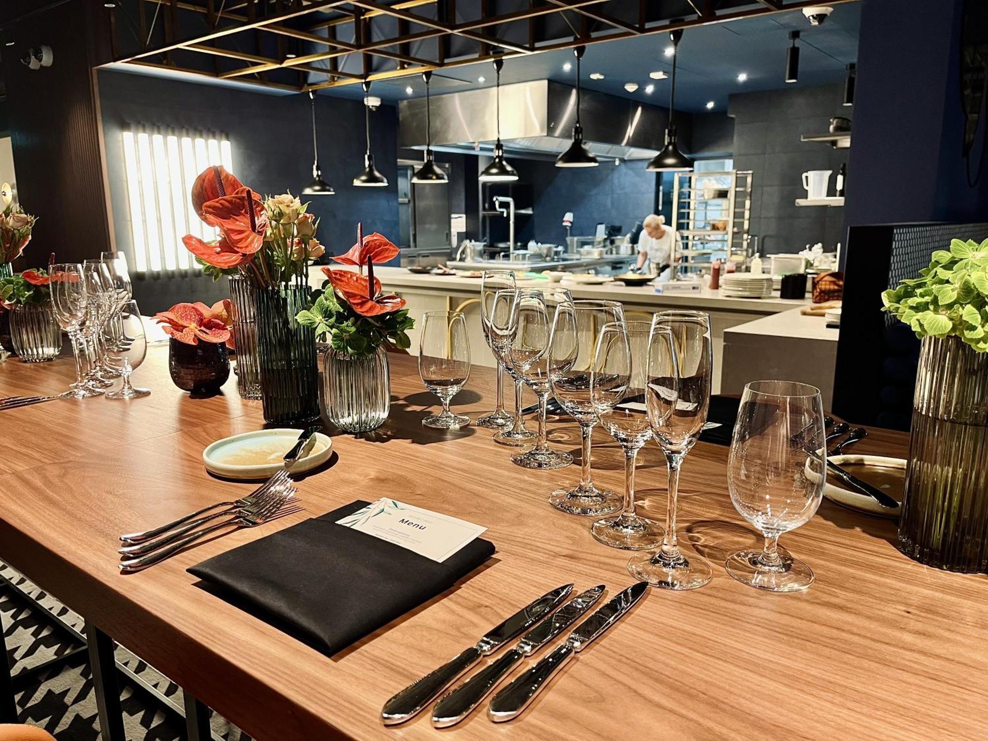 Aparthotel Royal Tulip Warsaw Centre Exterior foto The photo shows a beautifully arranged dining area in a restaurant. There is a long wooden table set with elegant glassware, including wine glasses and water glasses. Each place setting includes polished silverware and a folded napkin with a card on 